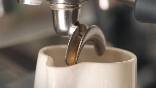 Fresh Black Coffee Pouring from Professional Machine Dispenser in Cup. 4K, Macro Slowmotion.