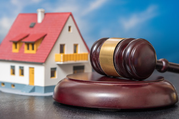 House auction concept. Gavel in front of a house model. - obrazy, fototapety, plakaty
