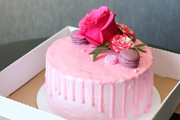 Tasty pink homemade cake decorated by rose and macarons