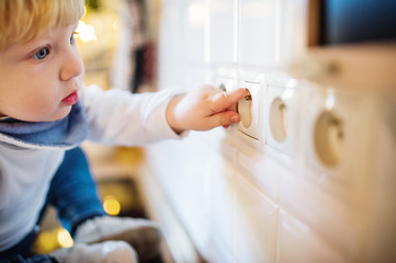 Toddler boy in dangerous situation at home. Child safety concept.