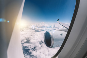 Aerial view of airplane flying above cloud, under navy sky from an airplane. View from plane's window with airways's jet and wing.