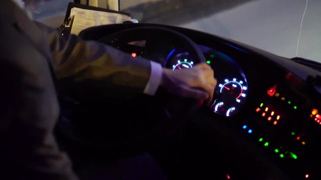 Man driving bus in a city street at night