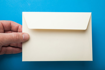 The hand holds an empty envelope on a blue background.