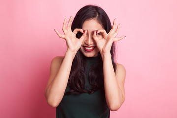 Asian woman do funny  double OK sign as glasses.