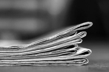 News - folded and stacked newspapers, side view, selective focus