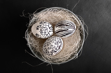 Black and white painted Easter eggs in the bowl on black background top view