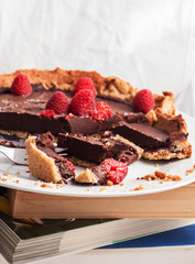 Plate with chocolate cake and raspberries on top of some books.