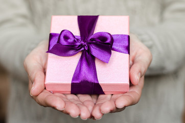 Young woman holds a gift box with a bow close up
