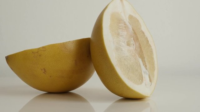 Two halves of Citrus maxima grandis close-up footage - Pieces of pomello fruit on white 