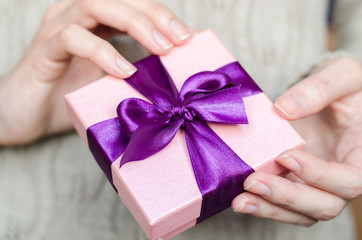 Young woman holds a gift box with a bow close up