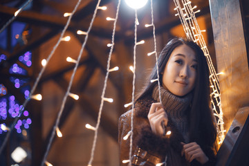 Portrait of young beautiful smiling Asian girl woman in brown knitted sweater and boho leather coat...