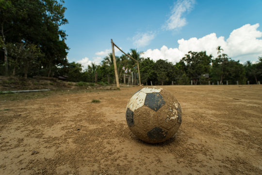 close up old football on ground at a dirt pitch