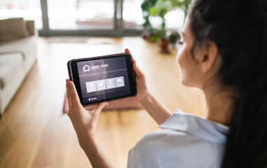 A woman holding a tablet with smart home screen.