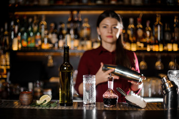 Female bartender shaking the cocktail on the bar counter