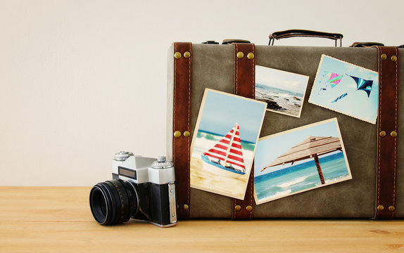 Image of old vintage luggage with vacation photos over wooden floor.