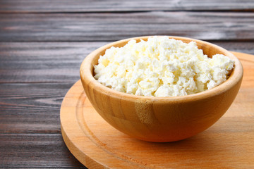 Home cottage cheese in a bowl on a wooden table.