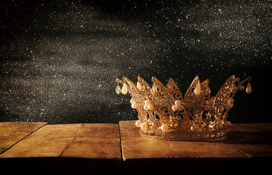 low key image of beautiful queen/king crown over wooden table. vintage filtered. fantasy medieval period.