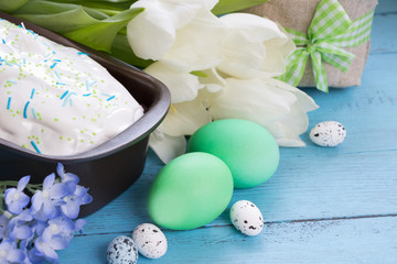 Easter background.Easter cakes,easter  eggs ,white tulips and spring flowers on blue wooden board