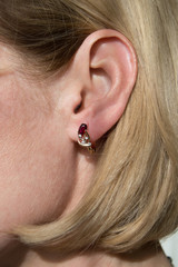 Golden earrings with dark red gemstone - garnet and few diamonds  in model's ear