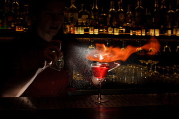 Female bartender spraying on and set fire to the cocktail