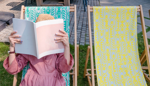 Close Up Teenage Girl Holding And Reading Book Or Magazine Sitting On Sea Chair In Vacation Time.