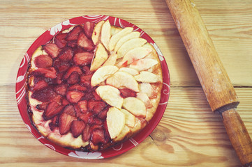 Combo pie of strawberries and apple on wooden background