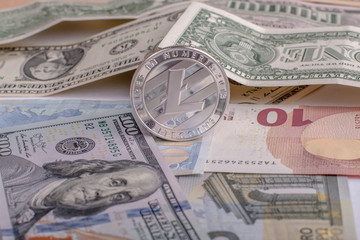 Cryptocurrency coin Litycoin on the euro and dollar banknotes. Close up with selective focus