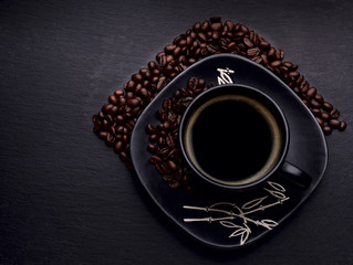 black cup of coffee with coffee beans on  wooden background