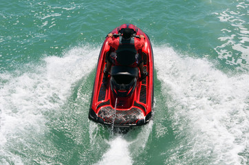 Obraz premium Angled overhead view of a speeding red jet ski running waves on the florida intra-coastal waterway off Miami Beach.