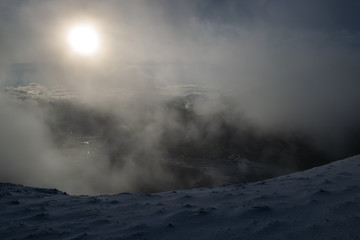 Foggy winters morning on snow capped hill in the sun