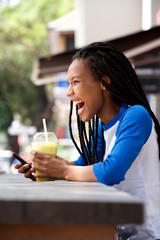attractive young woman laughing and using mobile phone at outdoor cafe