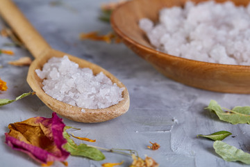 Composition of spa treatment on white background. Sea salt and flowers background, close up, top view, selective focus.