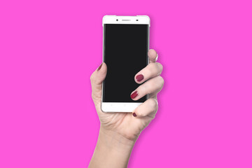 Left hand with red finger nails holds new modern smartphone with blank black screen - concept mobile communication young fresh lifestyle cellphone - isolated on pink background with copy space