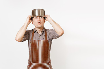 Fototapeta na wymiar Fun man in striped apron with silver stainless glossy aluminium empty stewpan, pan or pot on head isolated on white background. Male housekeeper or houseworker. Kitchenware, dishes, cuisine concept.