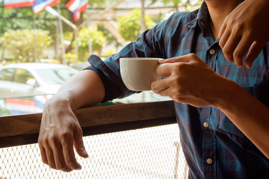 man holding hot latte coffee cup for break time after meeting at window seat of cafe