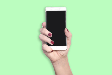 Right hand with red finger nails holds new modern smartphone with blank black screen - concept mobile communication young fresh lifestyle cellphone - isolated on green background with copy space