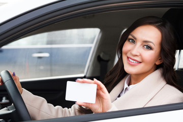 Portrait of smiling woman driver holding a white blank business card
