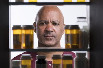Man looking at rows of prescription drugs in medicine cabinet