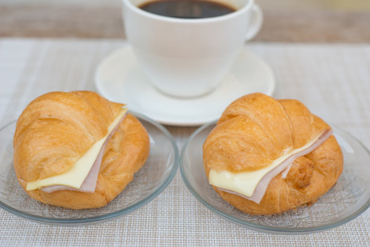 Ham and cheese croissant with coffee background