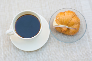 A cup of Black coffee with Ham and cheese croissant