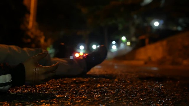 THE BODY OF A VIOLENCE VICTIM ON GROUND AT NIGHT, CAR PASSES