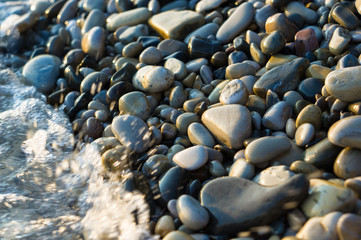 pebble stones on the sea beach, the rolling waves of the sea with foam