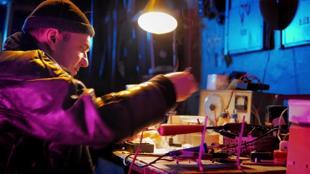 Master of repair working with old electronic staff at workshop with neon light