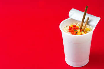 Take away noodles with vegetables on red background. Copyspace