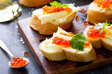 Festive snack. Sandwiches with red caviar, isolated on dark concrete background.