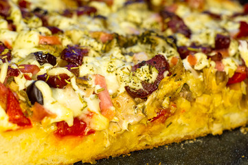 homemade pizza with peppers, plums, ham, sausage, cheese and spices, closeup