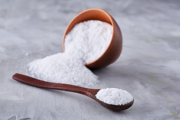 Conceptual composition of salt and pepper on spoons and bowls over light background, top view, close-up