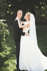 Lovely happy wedding couple, bride with long white dress posing in beautiful city