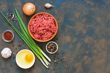 Beef minced meat with spices on a dark rustic background. Top view, copy space.