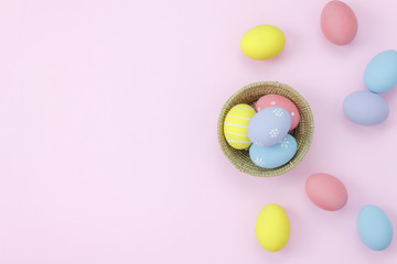 Table top view shot of arrangement decoration Happy Easter holiday background concept.Flat lay colorful bunny egg in wood basket on modern pink paper at home office desk.Space for creative design.